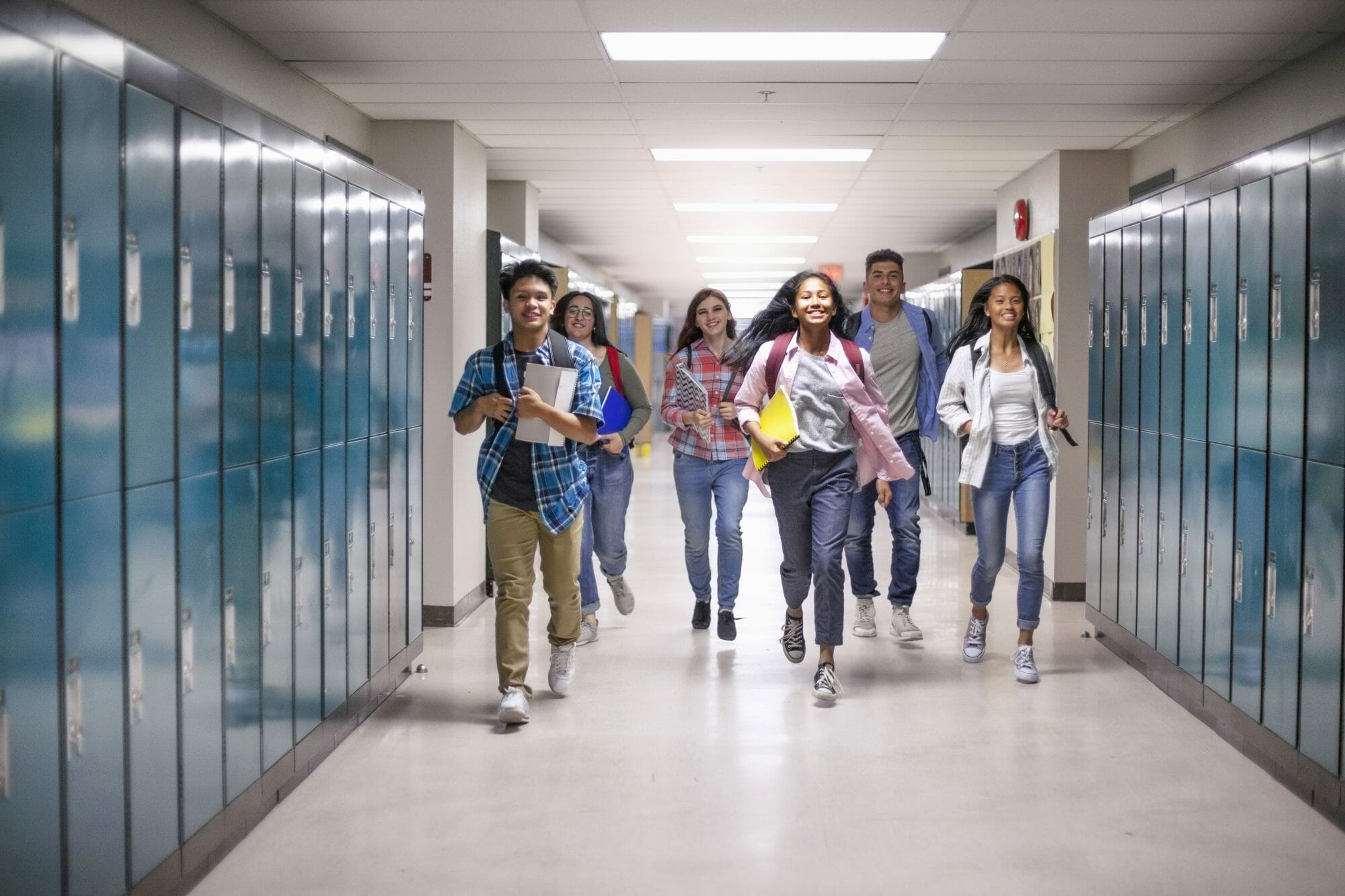 groups of teens walking down a locker-lined hallway