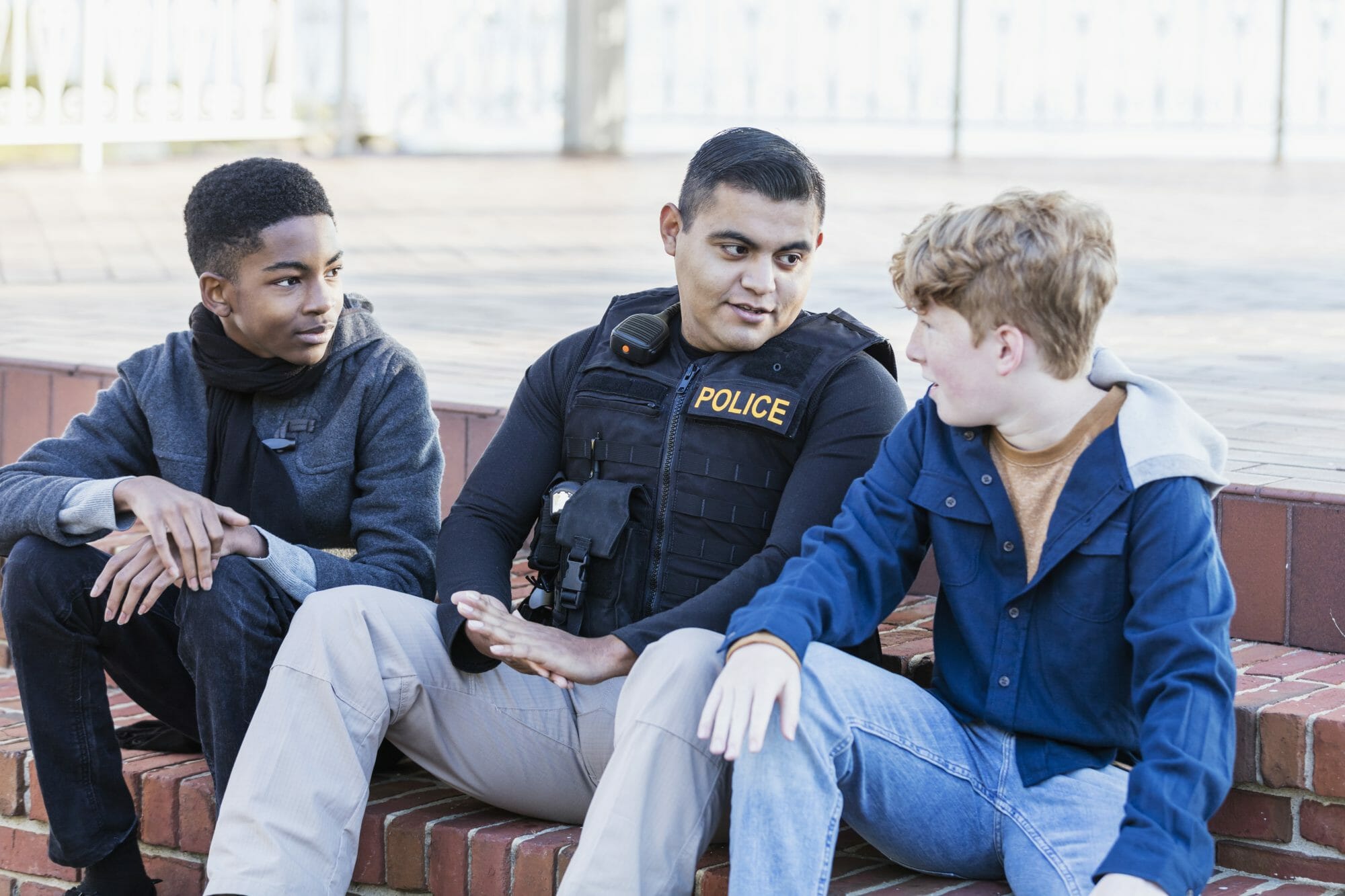 police officer and two young teens sitting together and talking